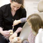 Dentist showing child how to use a toothbrush